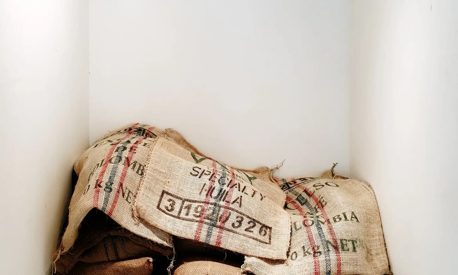 Stacked green coffee sacks awaiting receiving inspection in a commercial warehouse
