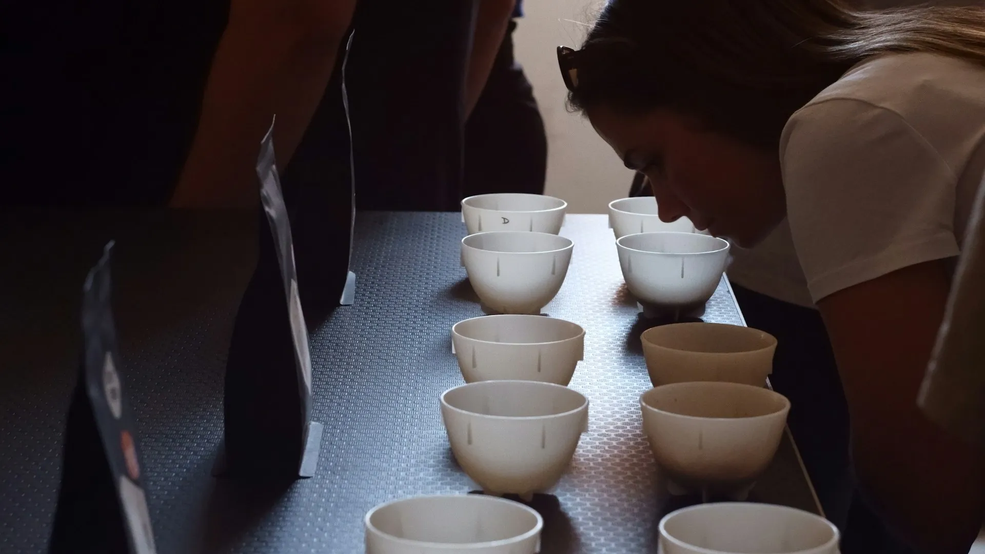 Evaluator smelling coffee samples in cupping bowls in a green coffee quality control lab